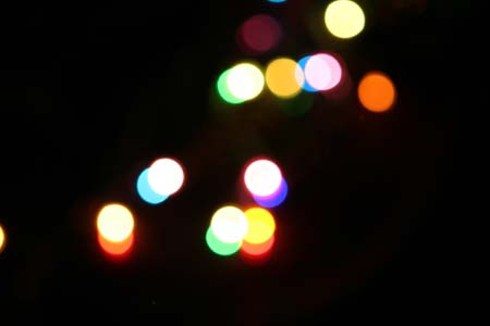 Shows the lit Christmas lights completely out-of-focus as blurry coloured lights.